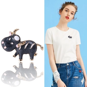 Broche cartoon taureau à émail noir et placage doré présentée sur un t-shirt blanc