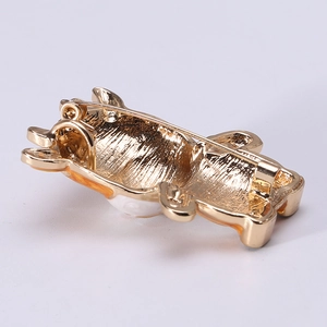 Golden cow brooch with orange enamel finish shown from a back view with safety pin