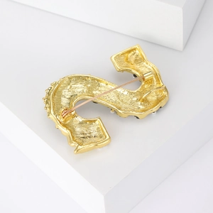 Élégante broche dorée lettre S avec détail d'épingle arrière sur fond blanc épuré