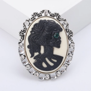 Vintage gothic brooch with silver floral frame, skull cameo, and sparkling rhinestones