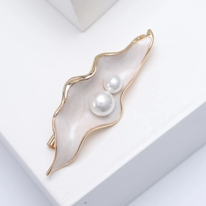 Vue détaillée d'une broche feuille en émail avec perles blanches et plaqué or