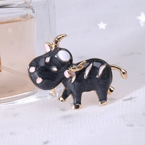 Détail macro d'une broche vache en émail noir avec bords dorés et texture marbrée