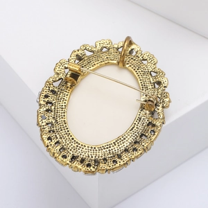 Macro shot showing the vintage gold-toned pin mechanism and texture of the oval brooch