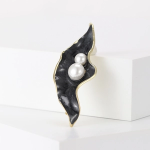 Vue détaillée d'une broche feuille en émail noir marbré et perles blanches