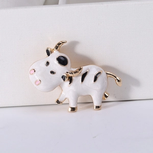 Détail de la broche petit veau blanc avec placage or et finition en émail brillant