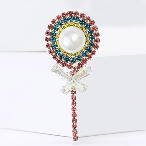 Sparkling rhinestone lollipop brooch with a large central pearl and crystal bow on white base