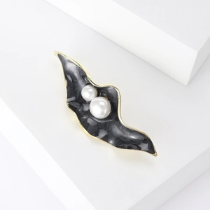 Detail view of wavy enamel brooch with dark marble pattern and lustrous white pearls