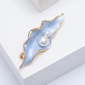 Detail of elegant leaf brooch with blue marble enamel finish and white pearls decoration
