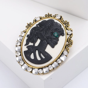 Vintage gothic cameo brooch with skull relief and crystals on a white pedestal