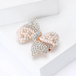 Detail of rose gold butterfly brooch featuring white faux pearls and sparkling rhinestones