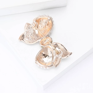 Detailed back view of golden bow brooch with pin buckle and pearl border