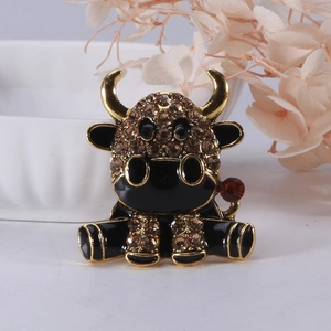 Primo piano di una spilla a forma di mucca in smalto nero con bordi dorati e strass