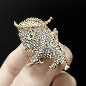 Close-up of golden bull brooch with sparkling rhinestones and green gem eye detail