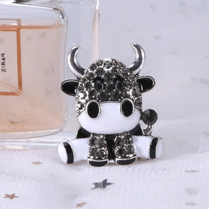 Dettaglio di una spilla a forma di mucca con strass scintillanti su tessuto bianco