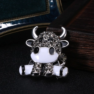 Dettaglio di graziosa spilla a mucca con smalto bianco e nero e strass grigi lucidi