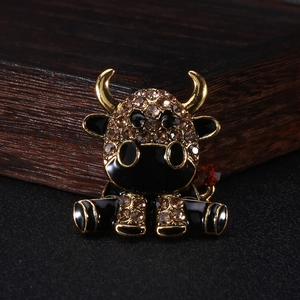 Dettaglio di una spilla a forma di mucca con strass color champagne e smalto su legno