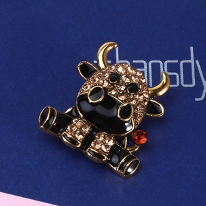 Macro di una spilla a forma di mucca con smalto nero e strass color champagne