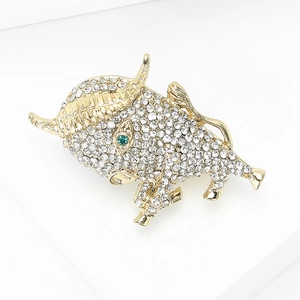 Close-up of a golden bull brooch with white rhinestones and a green gemstone eye