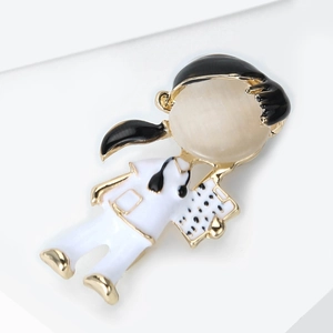 Detail of cartoon girl brooch with cat eye stone and black drip oil finish on gold alloy