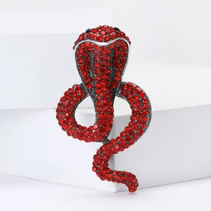 Close-up of a silver-plated cobra brooch featuring vibrant red rhinestones on a white podium