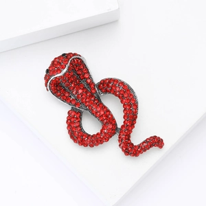 Macro shot of silver cobra brooch with vibrant red rhinestones on a white background