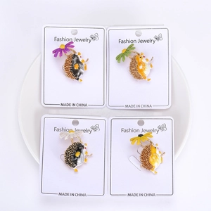 Detail of four colorful hedgehog enamel pins with daisy accents on white cards