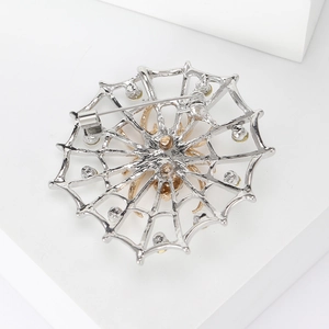 Broche toile d'araignée argentée avec araignée dorée et fermoir à épingle sur fond blanc