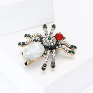 Vintage gold spider brooch with pear-shaped white stone and emerald green rhinestones