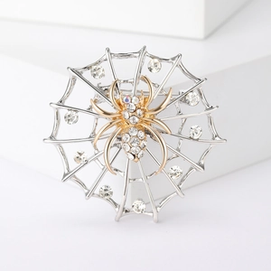 Broche toile d'araignée en strass avec araignée dorée sur socle géométrique blanc