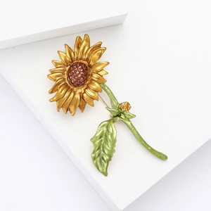 Minimalistische zonnebloem emaille broche met gouden bloemblaadjes op een witte basis