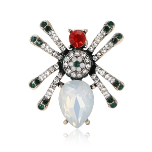 Vintage gold spider brooch featuring red gemstones and green crystal rhinestones