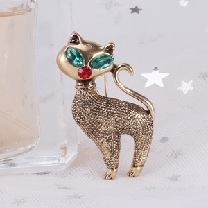 Detailed macro of vintage gold cat brooch with green gem eyes and textured alloy surface