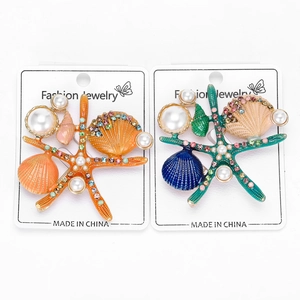 Détail de broches étoiles de mer et coquillages en émail coloré avec perles et cristaux