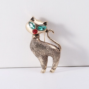 Detail of vintage cat brooch with green crystal eyes and textured gold-tone alloy finish