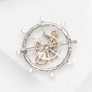 Detail view of the silver helm and golden anchor brooch with a secure safety pin clasp