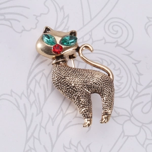 Close-up of vintage cat brooch with green rhinestone eyes and golden matte texture