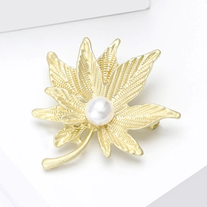 Eleganter goldener Ahornblatt-Anstecker mit weißer Perle auf einer weißen Oberfläche