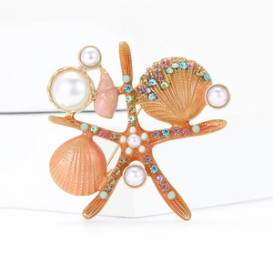 Broche étoile de mer orange avec perles et strass colorés sur un fond blanc neutre