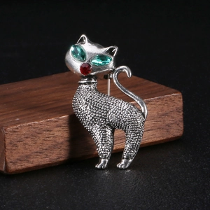 Close-up of retro silver cat brooch with green marquise rhinestones and textured metal