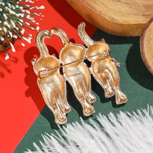 Festive golden alloy Christmas cat brooch set against a vibrant red and green background