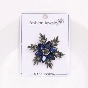 Élégante broche fleur en cristal bleu avec feuilles en alliage argenté sur présentoir