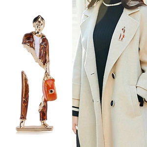 Künstlerische Emaille-Brosche mit abstrakter Figur an einem hellen Mantelaufschlag