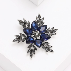 Élégante broche fleur argentée avec pétales en cristal bleu foncé et détail diamant