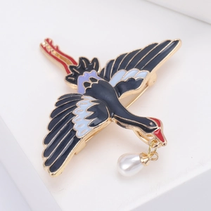 Broche grue élégante avec émail bleu et pendentif perle dans une pose de vol gracieuse