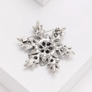 Broche flocon de neige vintage argentée avec cristaux bleus sur bloc blanc