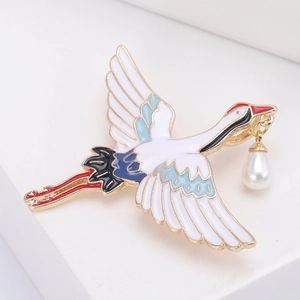 Élégante broche grue aux ailes émaillées avec perle pendante sur un bloc blanc