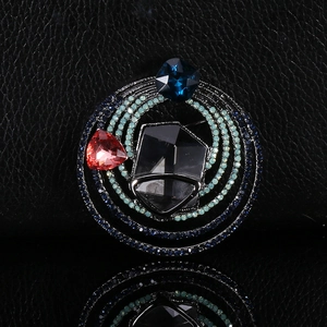 Macro shot of retro crystal brooch with colorful rhinestones on a black leather texture