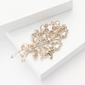 Close-up of the golden floral brooch back with a classic safety pin closure detail