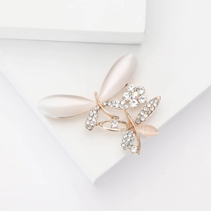 Broche libellule dorée élégante avec ailes en opale et strass brillants sur fond blanc