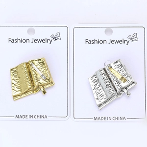 Detailed view of book and quill shaped lapel pins in gold and silver metal finishes